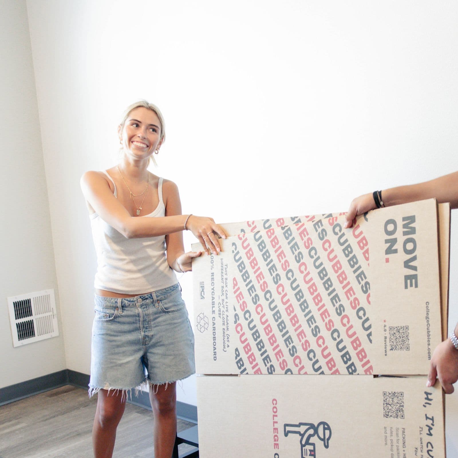 Student smiling with a Cubbies box in her dorm