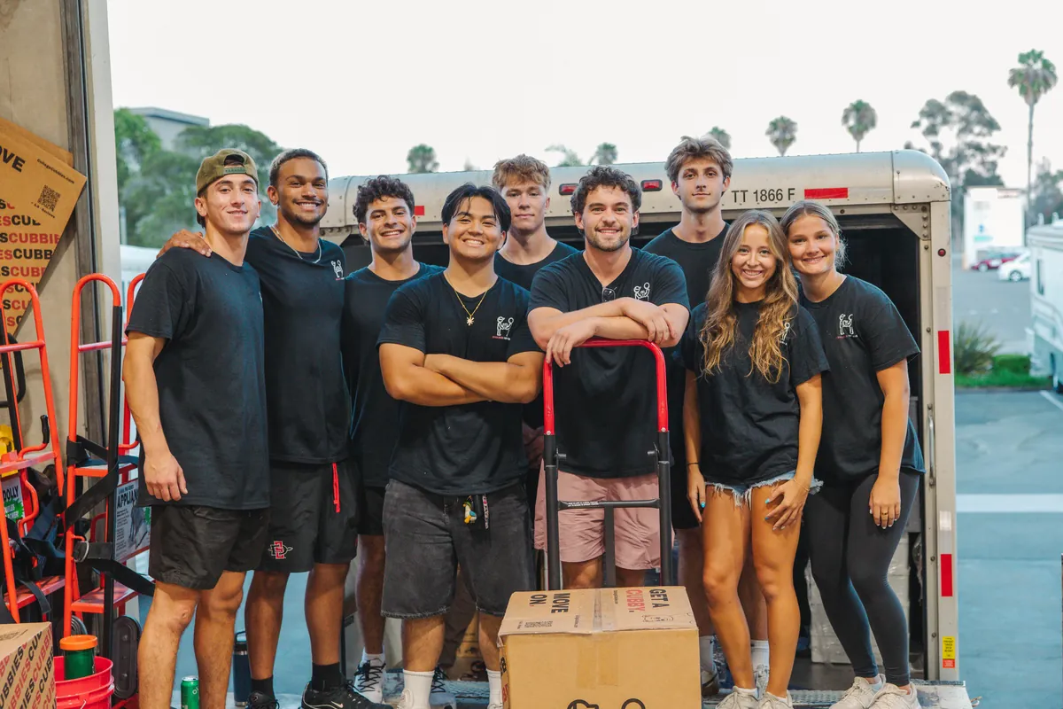 The College Cubbies move day crew smiling in front of the truck